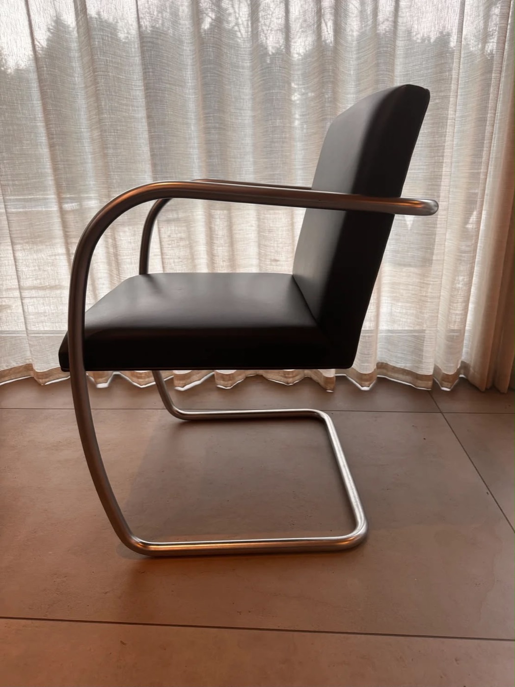 Knoll Brno Chair in black leather, side view showing the tubular cantilever frame, photographed in situ